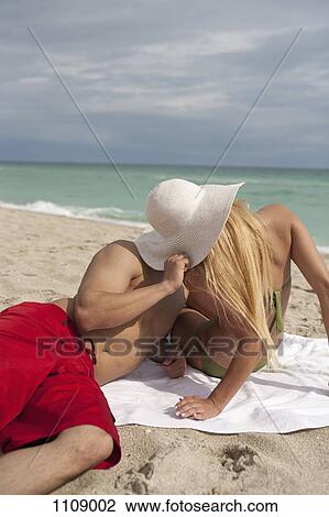 Stock Image - A young couple kissing on the beach. Fotosearch