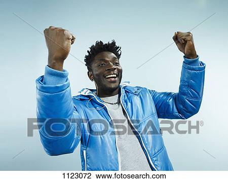 Stock Image - A young hip man with his arms raised in celebration. Fotosearch