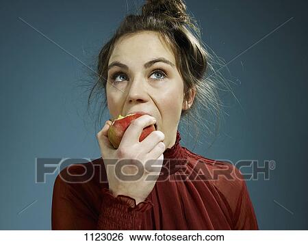 A young hip woman eating an apple View Large Photo Image Stock Photograph - A young hip woman eating an apple. Fotosearch