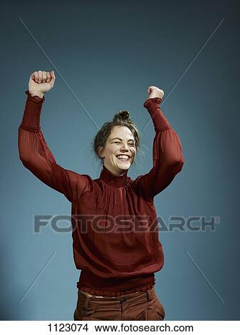 Picture - A young hip woman with her arms raised in celebration. Fotosearch