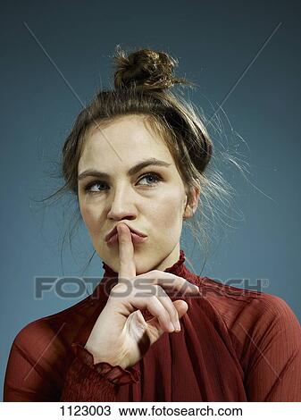 Stock Image - A young hip woman with her index finger on her lips, thinking. Fotosearch