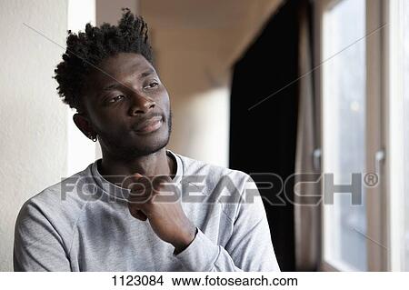 A young man looking contemplative while looking out a window View Large Photo Image Picture - A young man looking contemplative while looking out a window. Fotosearch
