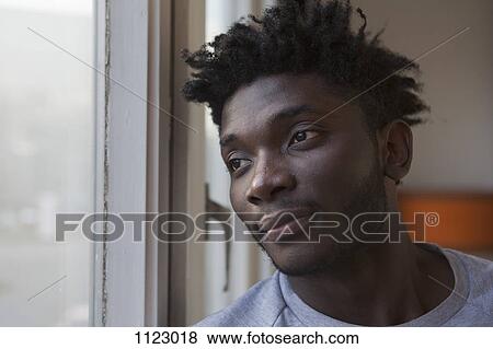 A young man looking out a window View Large Photo Image Stock Photo - A young man looking out a window. Fotosearch