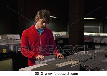 A young man searching through records in a darkened record shop View Large Photo Image Stock Image - A young man searching through records in a darkened record shop. Fotosearch