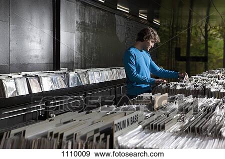 A young man searching through records in a record store View Large Photo Image Stock Photo - A young man searching through records in a record store. Fotosearch