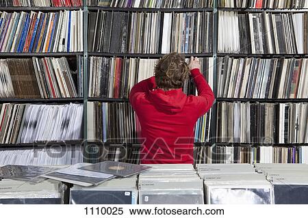 Stock Photography - A young man selecting a record from a shelf in a record store. Fotosearch