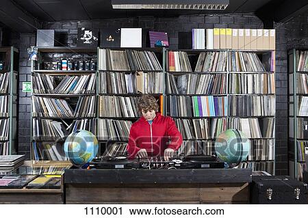 A young man using a sound mixer and DJ decks at a record store View Large Photo Image Stock Image - A young man using a sound mixer and DJ decks at a record store. Fotosearch