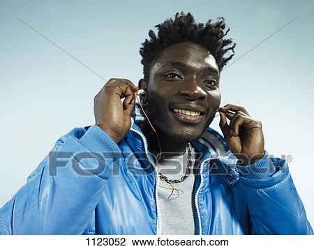 A young man wearing a vintage ski jacket and putting in earbuds View Large Photo Image Stock Image - A young man wearing a vintage ski jacket and putting in earbuds. Fotosearch