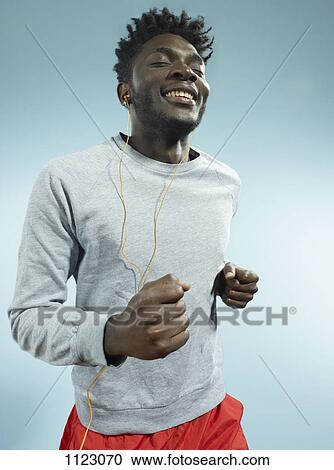Stock Image - A young man wearing earbuds and running. Fotosearch