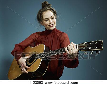 A young woman playing an acoustic guitar View Large Photo Image Stock Image - A young woman playing an acoustic guitar. Fotosearch