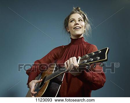 Stock Image - A young woman playing an acoustic guitar. Fotosearch