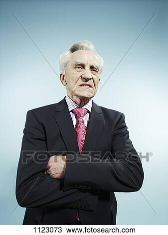 An elegant senior man with his arms crossed looking displeased View Large Photo Image Stock Image - An elegant senior man with his arms crossed looking displeased. Fotosearch
