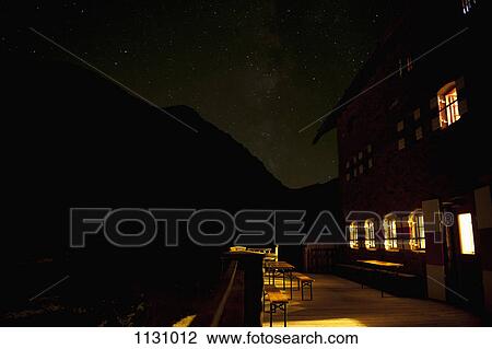 An illuminated building against a silhouetted mountain and starry sky View Large Photo Image Stock Image - An illuminated building against a silhouetted mountain and starry sky. Fotosearch