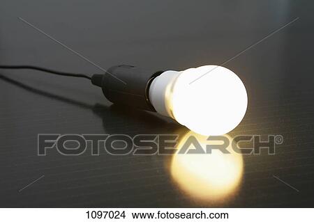 Picture - An illuminated light bulb on a solar panel. Fotosearch