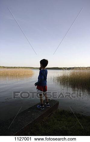 Boy standing at edge of lake View Large Photo Image Stock Image - Boy standing at edge of lake. Fotosearch