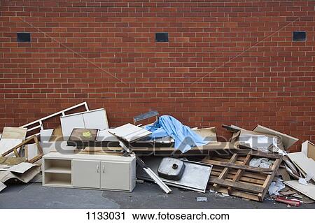 Broken furniture and scraps of garbage piled up against a brick wall View Large Photo Image Stock Image - Broken furniture and scraps of garbage piled up against a brick wall. Fotosearch