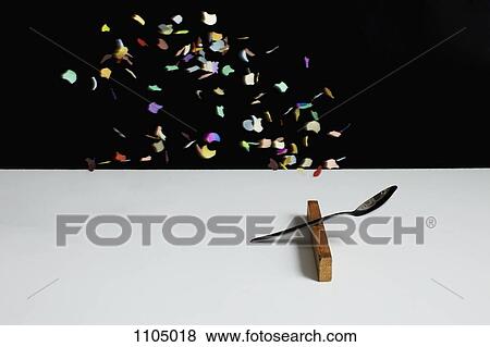 Confetti floating above a spoon leaning on a wooden block View Large Photo Image Stock Photo - Confetti floating above a spoon leaning on a wooden block. Fotosearch