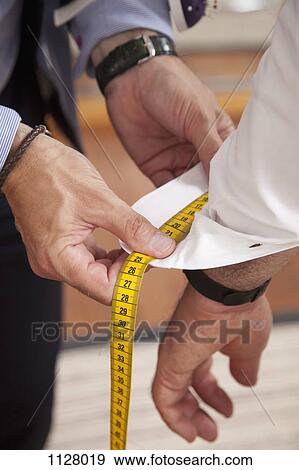 Detail of a tailor measuring the shirt cuff of a man View Large Photo Image Stock Photo - Detail of a tailor measuring the shirt cuff of a man. Fotosearch