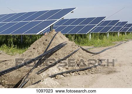 Stock Image - Detail of pipes and solar panels being installed in a field. Fotosearch