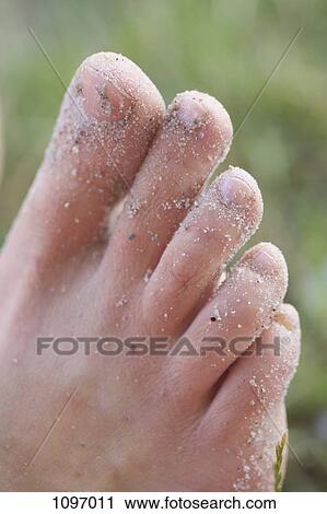 Stock Image - Detail of sand on the foot of a woman. Fotosearch