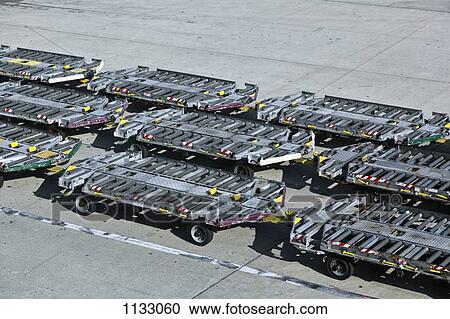 Empty baggage trailers on an airport tarmac View Large Photo Image Stock Image - Empty baggage trailers on an airport tarmac. Fotosearch