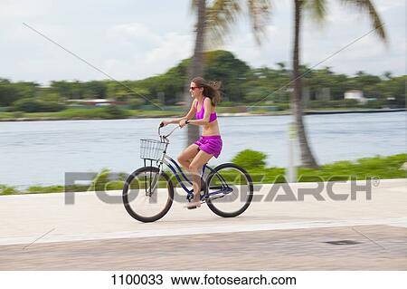 Stock Image - Girl cycling barefoot. Fotosearch