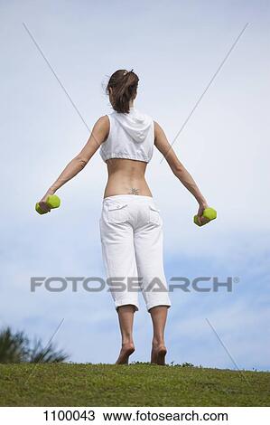 Girl in field lifting dumbbells View Large Photo Image Stock Image - Girl in field lifting dumbbells. Fotosearch