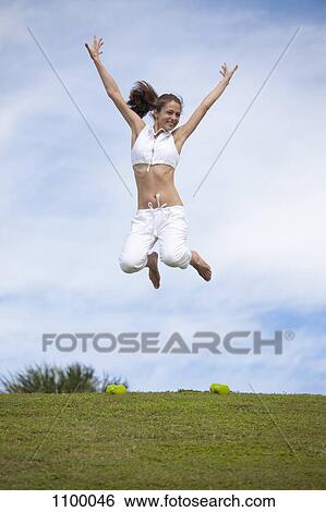 Girl jumping in mid-air in field View Large Photo Image Stock Photograph - Girl jumping in mid-air in field. Fotosearch