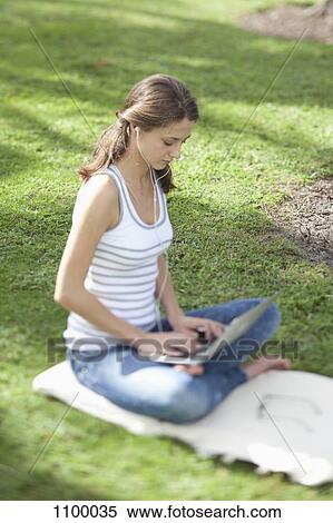 Girl on grass with legs crossed using laptop View Large Photo Image Stock Photography - Girl on grass with legs crossed using laptop. Fotosearch