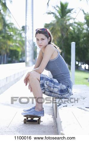 Girl sitting with feet resting on skateboard View Large Photo Image Stock Photograph - Girl sitting with feet resting on skateboard. Fotosearch