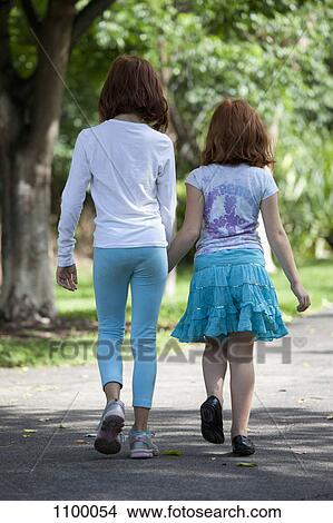 Girls walking through park hand in hand View Large Photo Image Picture - Girls walking through park hand in hand. Fotosearch