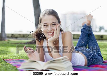 Happy girl in park lying down with book View Large Photo Image Stock Photo - Happy girl in park lying down with book. Fotosearch