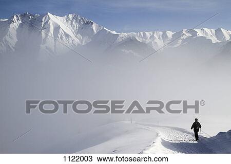 Hiking on trail by snowy mountain range View Large Photo Image Stock Image - Hiking on trail by snowy mountain range. Fotosearch