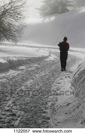 Lone hiker walking along snow path View Large Photo Image Stock Photo - Lone hiker walking along snow path. Fotosearch