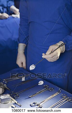 Stock Photo - Midsection of a man holding a surgical instrument. Fotosearch