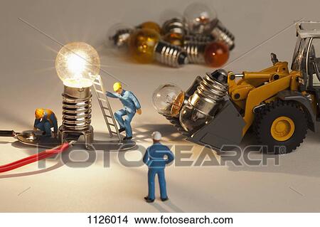 Picture - Miniature electrician figurines working on an illuminated light bulb. Fotosearch