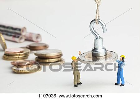 Miniature workmen guiding a hanging two Euro coin down View Large Photo Image Stock Photograph - Miniature workmen guiding a hanging two Euro coin down. Fotosearch