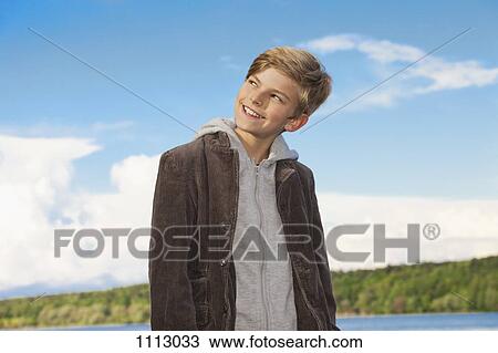 Stock Image - Portrait of a boy looking away and smiling mischievously. Fotosearch