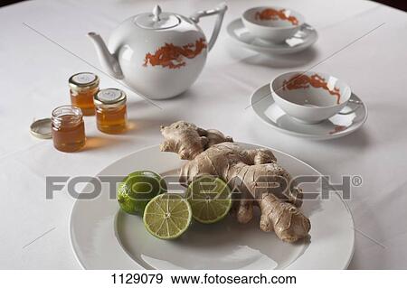 Raw ginger and limes on a plate next to teapot and cups View Large Photo Image Stock Photo - Raw ginger and limes on a plate next to teapot and cups. Fotosearch