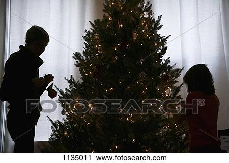 Silhouette of mother and daughter decorating a Christmas tree View Large Photo Image Stock Image - Silhouette of mother and daughter decorating a Christmas tree. Fotosearch