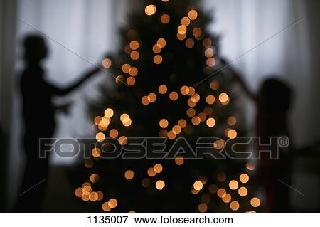 Stock Photo - Silhouette of mother and daughter decorating a Christmas tree. Fotosearch