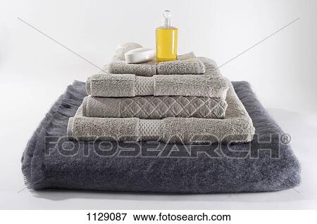 Stock Photo - Stacks of folded towels with a bar of soap and massage oil on top. Fotosearch