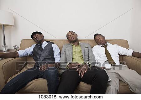 Stock Photography - Three exhausted friends asleep on a sofa. Fotosearch