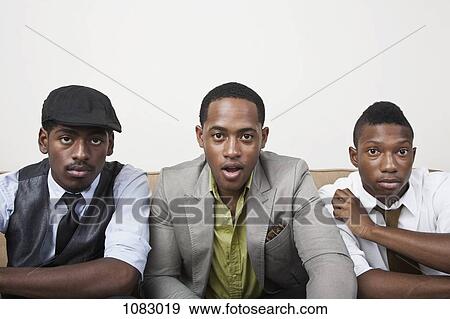 Three men sitting side by side looking surprised View Large Photo Image Stock Photo - Three men sitting side by side looking surprised. Fotosearch