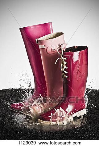 Three pink rubber boots splashing in a puddle View Large Photo Image Stock Photo - Three pink rubber boots splashing in a puddle. Fotosearch