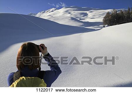 Stock Photo - Tourist takes photos of snowy landscape. Fotosearch