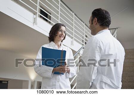 Two doctors talking on a staircase View Large Photo Image Stock Image - Two doctors talking on a staircase. Fotosearch
