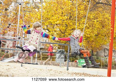 Two girls on swings holding hands View Large Photo Image Stock Photo - Two girls on swings holding hands. Fotosearch