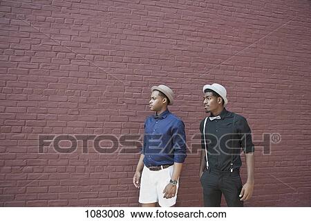 Two handsome young black men walking next to a brick wall View Large Photo Image Stock Photo - Two handsome young black men walking next to a brick wall. Fotosearch