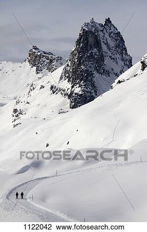 Stock Image - Two hikers make their way along snow path. Fotosearch